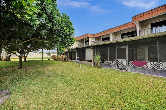 view of yard with a sunroom and a balcony