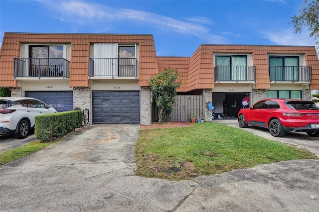 townhome / multi-family property with a garage, brick siding, driveway, and mansard roof