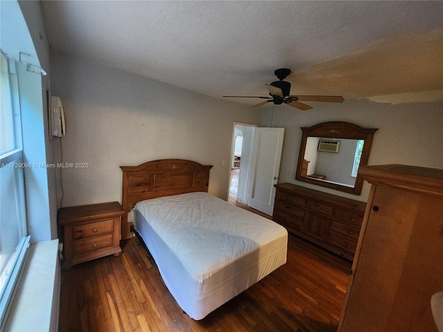 bedroom featuring dark wood-type flooring, ceiling fan, a wall mounted air conditioner, and a textured ceiling