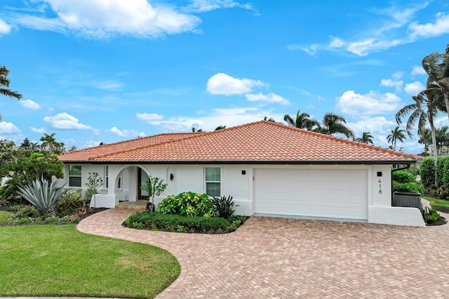 view of front of house featuring a front yard, decorative driveway, an attached garage, and stucco siding