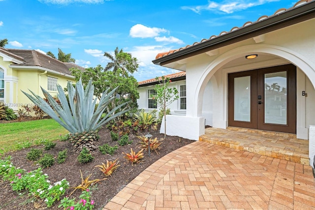 entrance to property with french doors, a tile roof, and stucco siding