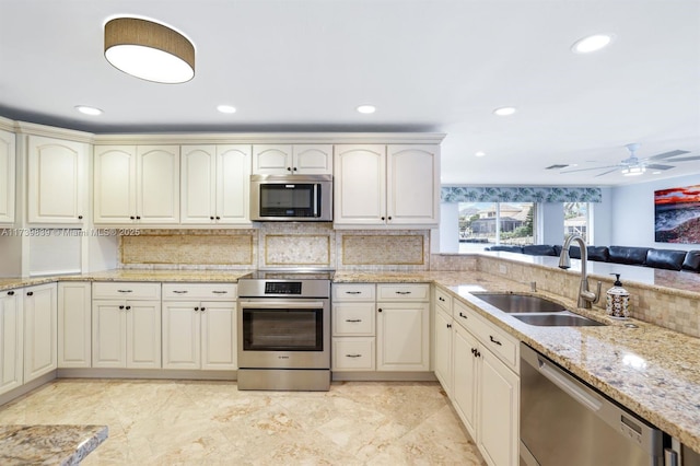 kitchen with light stone counters, tasteful backsplash, recessed lighting, appliances with stainless steel finishes, and a sink