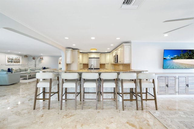 kitchen featuring stainless steel appliances, a breakfast bar, visible vents, open floor plan, and marble finish floor