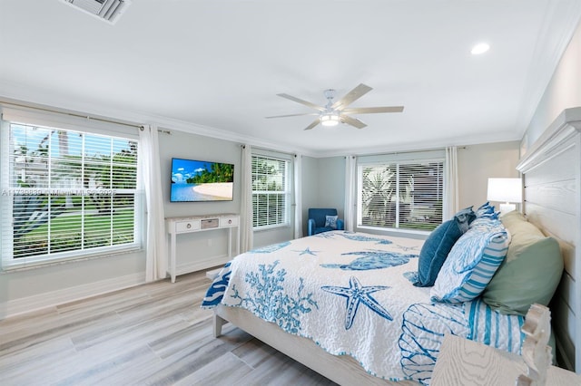 bedroom featuring ornamental molding, multiple windows, and light wood-style flooring