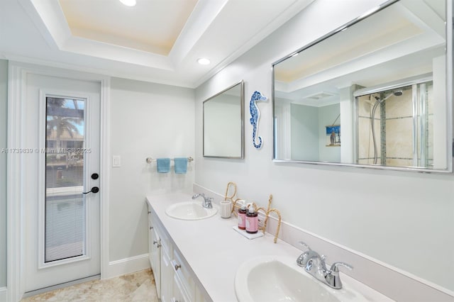 bathroom featuring double vanity, a tray ceiling, a sink, and baseboards