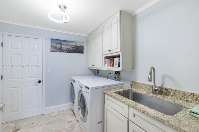 washroom with a sink, cabinet space, crown molding, and washer and dryer