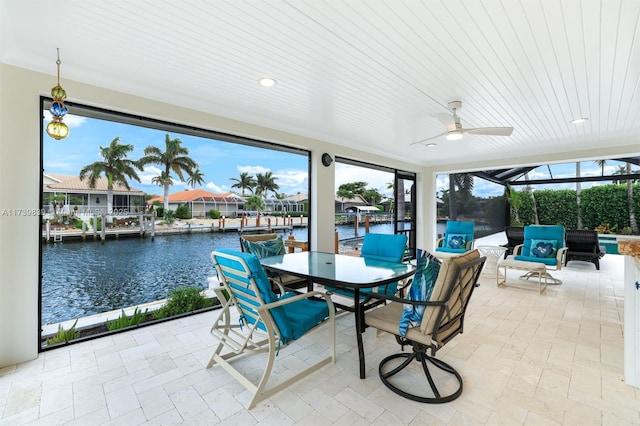 sunroom / solarium with a ceiling fan and a water view