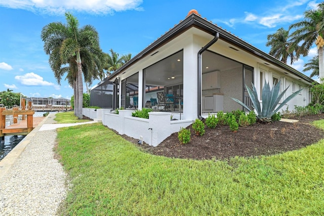 view of property exterior featuring glass enclosure, a yard, and stucco siding