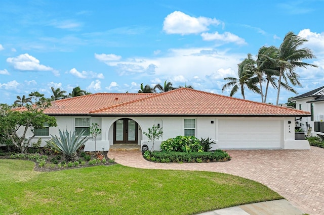 view of front of house featuring french doors, decorative driveway, stucco siding, a front yard, and a garage