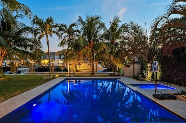 pool at dusk with a lawn and an outdoor structure