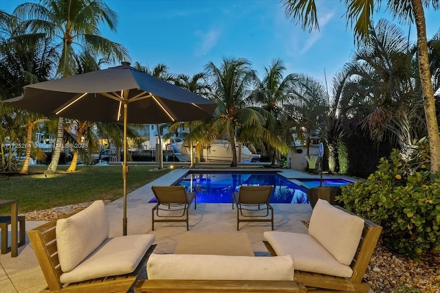 pool at dusk with a lawn and a patio area