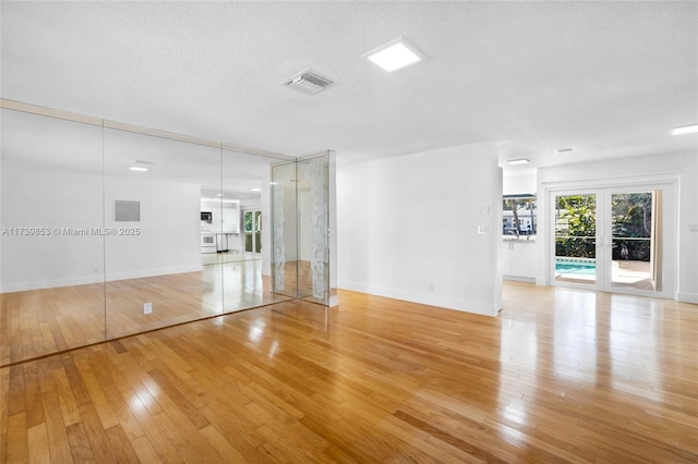 unfurnished living room featuring a textured ceiling and light wood-type flooring