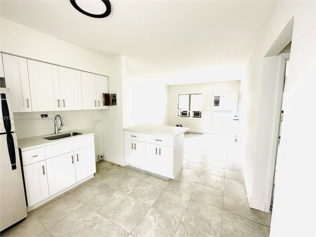 kitchen with white fridge, sink, white cabinets, and kitchen peninsula