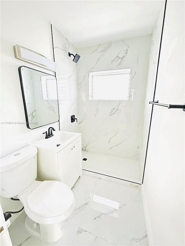 bathroom with a tile shower, vanity, and toilet