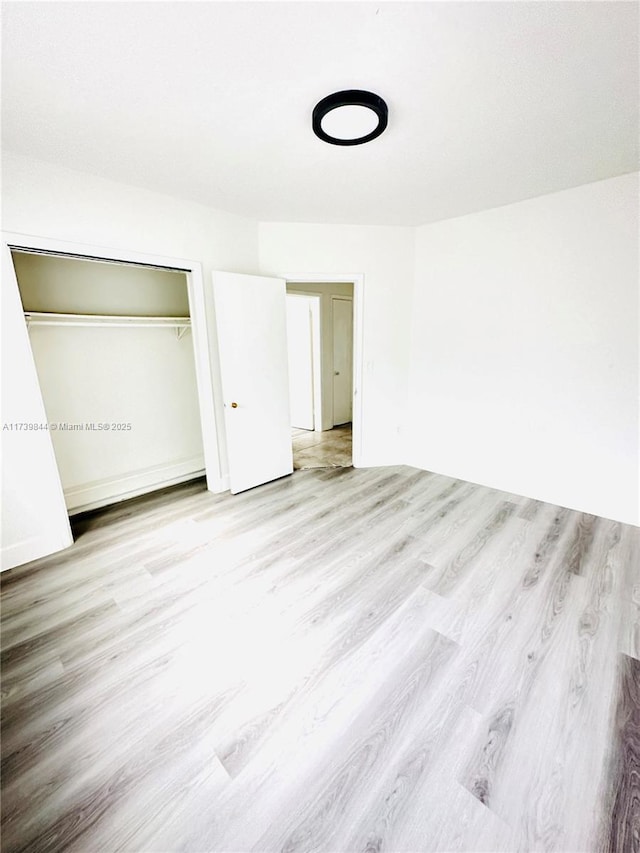 unfurnished bedroom featuring light wood-type flooring and a closet