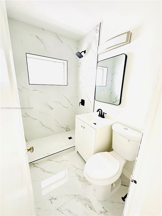 bathroom featuring vanity, a tile shower, and toilet