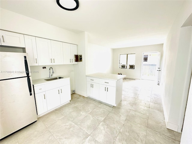 kitchen with white cabinetry, white fridge, sink, and kitchen peninsula