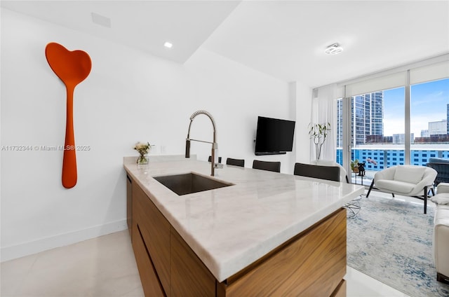 kitchen with light stone counters, floor to ceiling windows, and sink