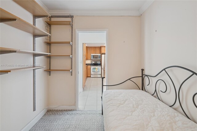 bedroom with crown molding, stainless steel fridge, and light tile patterned floors