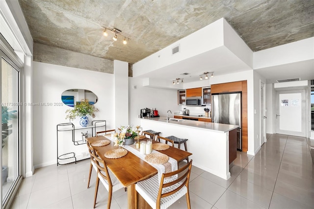 dining room featuring sink, light tile patterned floors, and track lighting