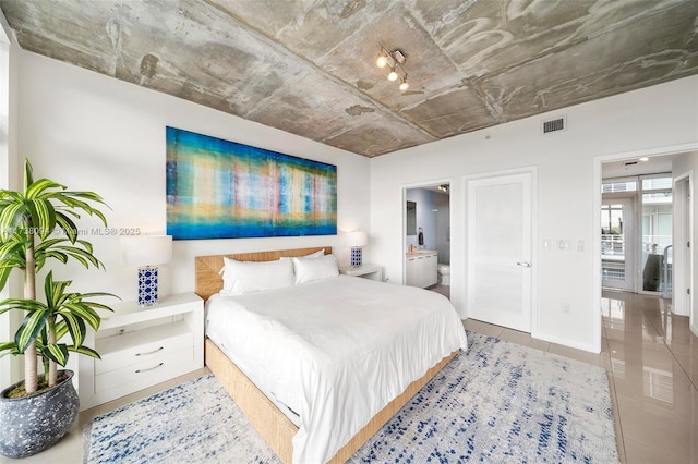 bedroom with ensuite bath and light tile patterned floors