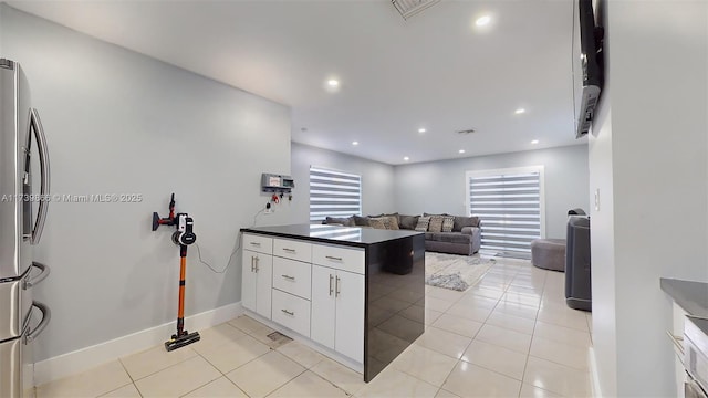 kitchen with white cabinetry, light tile patterned floors, stainless steel fridge, and kitchen peninsula