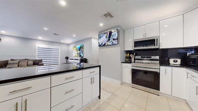 kitchen with light tile patterned flooring, appliances with stainless steel finishes, tasteful backsplash, and white cabinets