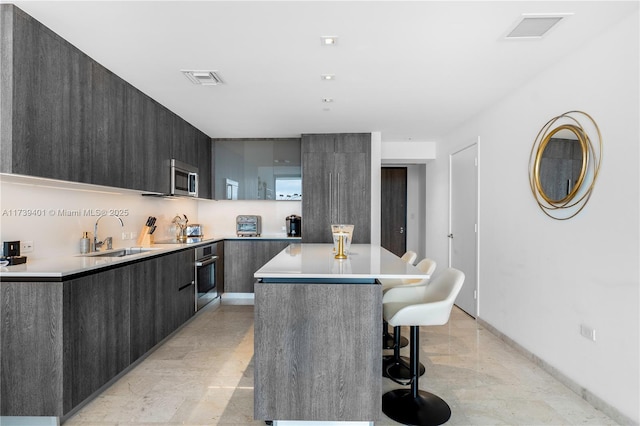 kitchen with sink, a breakfast bar area, stainless steel appliances, and a kitchen island