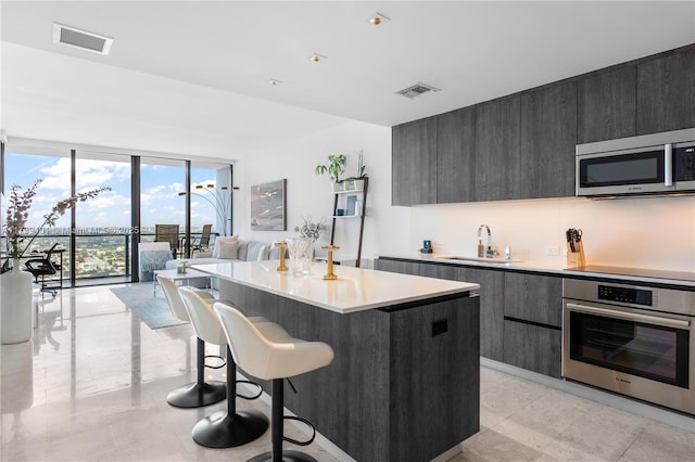 kitchen with sink, stainless steel appliances, a center island, expansive windows, and a kitchen bar