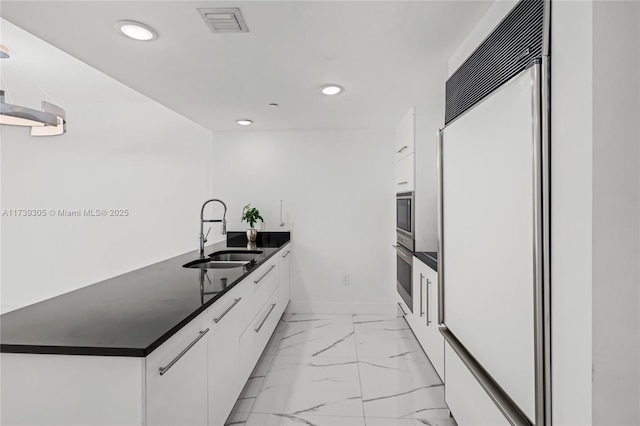 kitchen with white cabinetry, stainless steel oven, paneled built in fridge, and sink