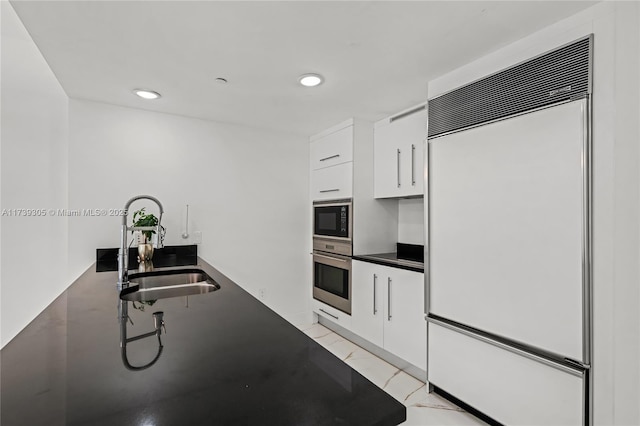 kitchen with built in appliances, sink, and white cabinets