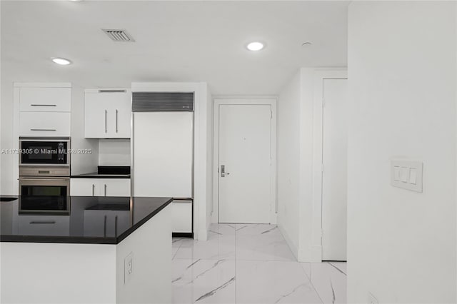 kitchen featuring white cabinetry and paneled refrigerator