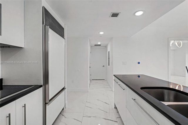 kitchen featuring sink, white cabinets, and paneled built in refrigerator