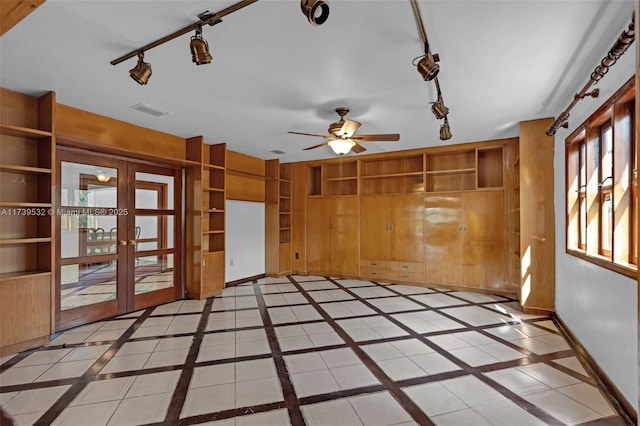 tiled empty room featuring built in shelves, wooden walls, french doors, and ceiling fan