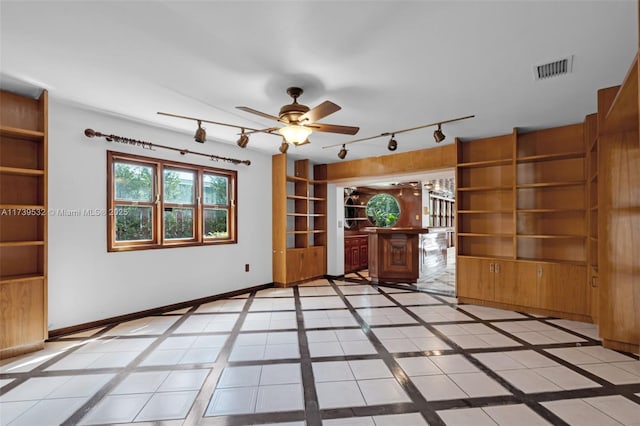 unfurnished living room featuring built in shelves and ceiling fan