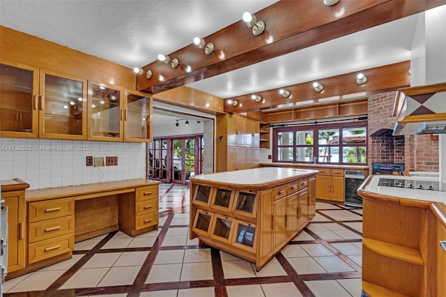 kitchen with tasteful backsplash, built in desk, tile counters, a kitchen island, and beverage cooler