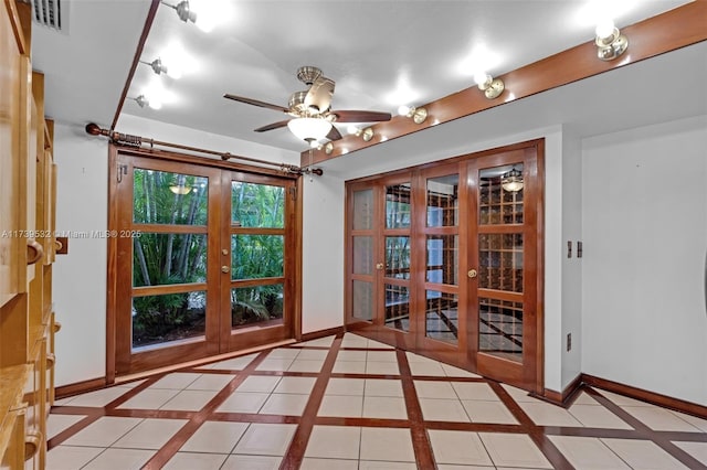 tiled spare room featuring ceiling fan and french doors