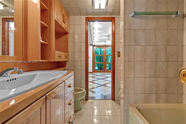 bathroom with vanity, a tub, and tile walls