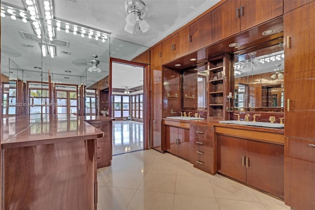 kitchen with wooden walls, sink, light tile patterned floors, and ceiling fan