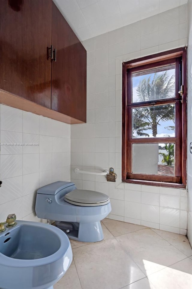 bathroom featuring tile walls, tile patterned floors, toilet, and a bidet