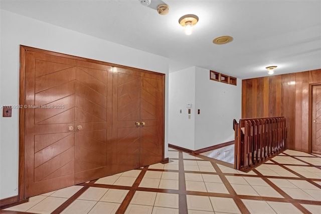 corridor with light tile patterned floors and wood walls