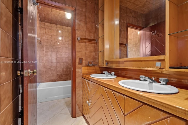 bathroom with tile patterned flooring, vanity, tile walls, and tiled shower / bath