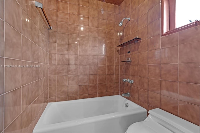 bathroom featuring tiled shower / bath combo, tile walls, and toilet