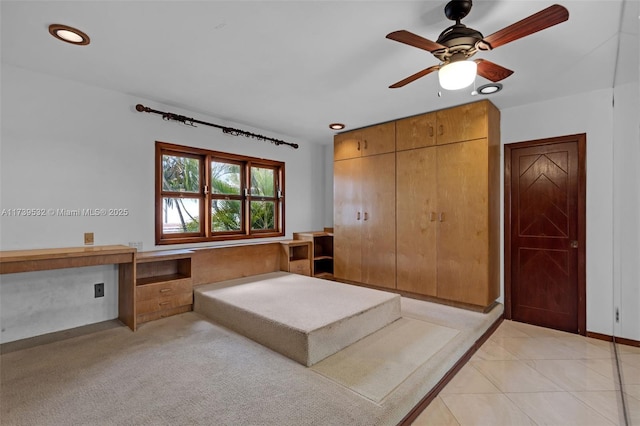 interior space with ceiling fan, built in desk, a closet, and light tile patterned floors