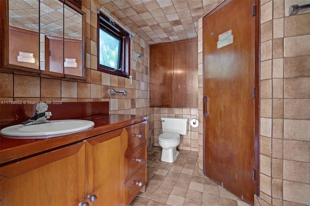 bathroom with vanity, tile walls, and toilet