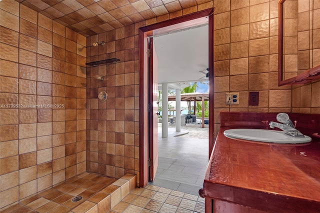 bathroom featuring sink, ceiling fan, tile walls, tiled shower, and tile patterned floors