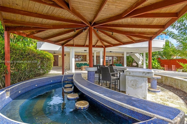 view of swimming pool featuring ceiling fan, exterior bar, and a patio