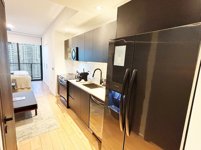 kitchen featuring sink, decorative backsplash, stainless steel appliances, floor to ceiling windows, and light hardwood / wood-style flooring