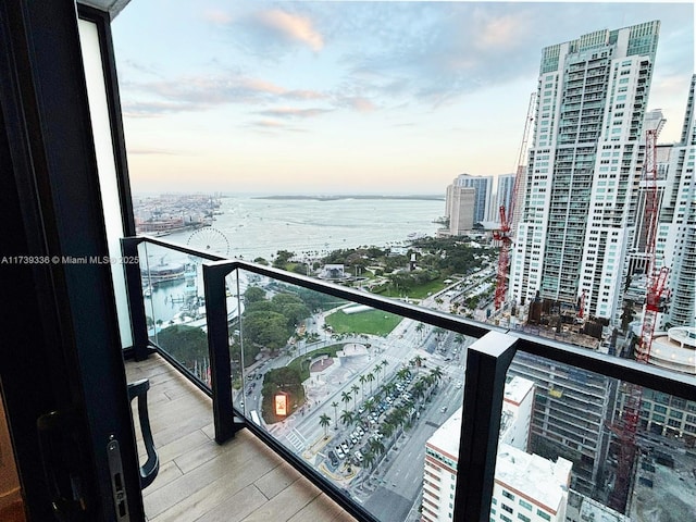 balcony at dusk featuring a water view