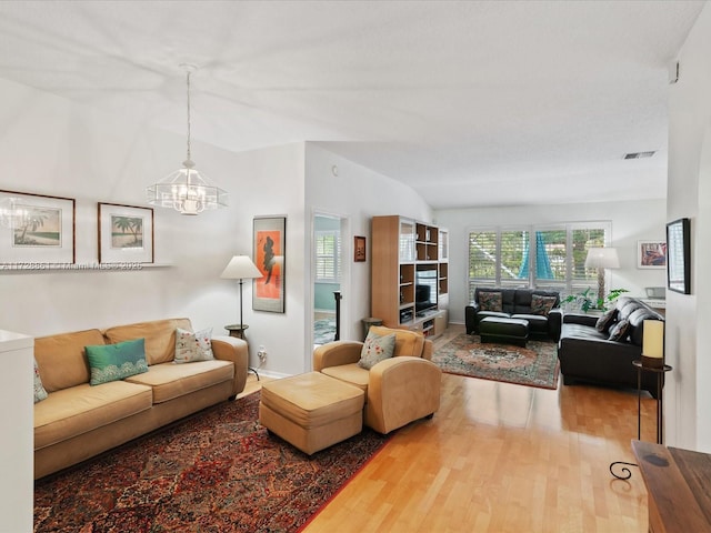 living room with vaulted ceiling, a chandelier, and hardwood / wood-style floors